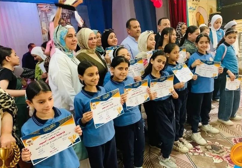 طالبات المرحلة الابتدائية يحملن شهادات التفوق مع المعلمات